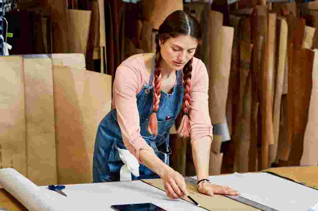 Worker Using Cardboard Paper And Pencil To Mark On Textile